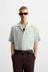Camisa de hombre relaxed fit con cuello bowling y manga corta, confeccionada en tejido fluido con mezcla de viscosa a rayas verticales en tonos verde y blanco.