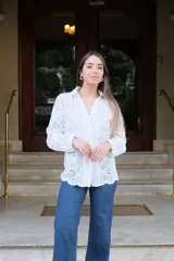 Camisa blanca de manga larga con cuello camisero y cierre frontal con botones. Detalle de bordados perforados combinados a tono.