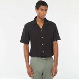 Camisa negra de manga corta con cuello solapa y cierre frontal con botones de madera.