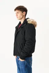 Campera negra con capucha con borde de piel sintética color beige, cierre frontal con cremallera y botones a presión, bolsillos laterales con solapa y puños acanalados.
