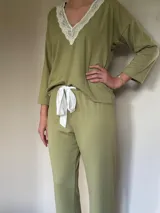 Pijama verde con textura acanalada, compuesto por un top de mangas largas con escote en V con puntilla blanca y un pantalón recto con lazo blanco en la cintura.