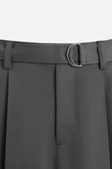 Pantalón negro de corte ancho con cinturón de tela con hebilla metálica y pliegues frontales.