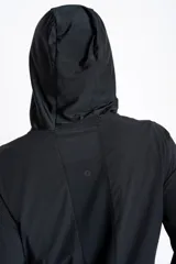 Campera deportiva negra con capucha, cierre frontal y textura microcuadriculada. Presenta puños y ruedo ajustados.