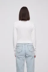 Remera de manga larga color beige con estampado gráfico de mariposa en el frente.