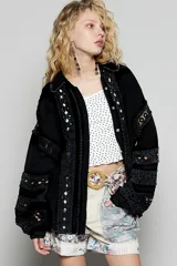 Blusa blanca de corte amplio con cuello camisero y cierre frontal de botones. Presenta detalles de encaje calado (broderie) en los bordes y en las mangas estilo kimono.