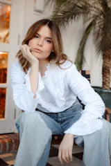 Camisa blanca de algodón con volados en el pecho y cuello, botones nacarados y mangas largas con puños elásticos.