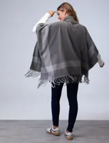 Capa de tejido soft color gris, con cuello alto, hebilla y terminación de ruedo con flecos.