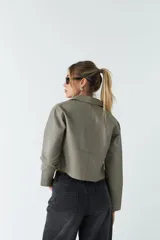 Sobrecamisa cropped de cuero sintético color negro, con cuello clásico, cierre frontal con botones, mangas largas y bolsillos frontales con solapa.