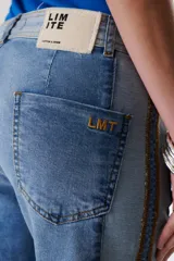 Pantalón de jean azul con paneles en distintos tonos de azul y marrón, corte recto y terminación desflecada.