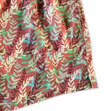 Short de baño blanco con estampado de hojas de palmera en tonos verde, rojo y amarillo.