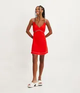 Vestido corto rojo de lino con tirantes dobles y costuras en contraste. Tiene una abertura debajo del busto y pespuntes vistos en el ruedo.