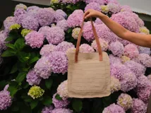 Bolso tipo tote de cuero color beige con textura tipo piel de cocodrilo. Tiene doble asa corta color marrón y un bolsillo externo. El interior contiene tres bolsillos y un llavero. Incluye correa larga extraíble.
