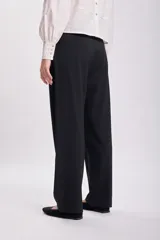 Pantalón de vestir negro, de corte carrot, con bolsillos laterales y traseros.