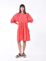 Vestido corto color coral con corte escalonado y mangas abullonadas.