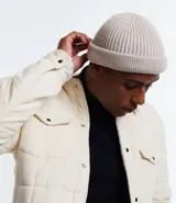 Gorro corto tipo beanie color beige, tejido en lana acrílica con textura acanalada.
