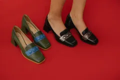 Zapato de cuero negro con aplique plateado y botones forrados en cuero.
