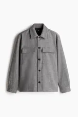 Sobrecamisa gris de corte recto, con cuello inglés, tapeta lisa y bolsillos superiores con solapa. Mangas largas con abertura y botón en los puños, canesú en la espalda y bajo recto.