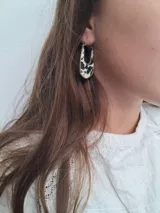 Par de aros colgantes con forma geométrica, con interior de cuero sintético negro con textura de piel de cocodrilo y borde dorado.