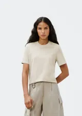 Remera color beige de corte clásico, con cuello redondo y mangas cortas.