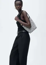 Mono largo negro con cuello redondo, sin mangas, trabillas y cinturón con hebilla.