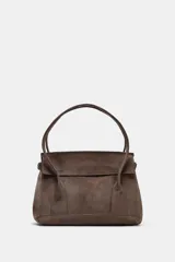 Bolso tipo city bag color marrón topo, con doble asa corta, cierre con solapa e imán, bolsillo interior con cremallera y laterales ajustables con hebillas metálicas.