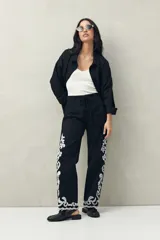 Pantalón recto negro de algodón con bordado artesanal blanco a contratono en los laterales y ruedo.