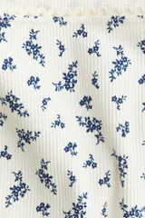 Top blanco de punto acanalado con estampado floral azul, escote cuadrado con ribete de picot y mangas largas.