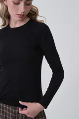 Remera de manga larga ajustada al cuerpo, color negro, con cuello redondo a la base y tejido acanalado.