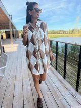 Vestido camisero corto con estampado de rombos en tonos beige, marrón y blanco. Tiene cuello camisero, cierre frontal con botones y corte holgado.