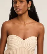 Blusa color beige sin breteles, confeccionada en viscolino con 15% de lino, con escote corazón, fruncidos y lastex en la espalda. La prenda tiene cuerditas aplicadas en el busto.