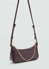 Bolso tipo baguette color beige, con asa corta de cadena dorada y cierre de cremallera superior.