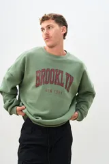 Buzo verde oliva con estampa en el frente con la palabra "Brooklyn" en color bordó y la frase "New York" en color gris.