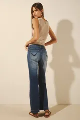 Jean de mujer color azul oscuro, tiro alto, corte oxford (o campana moderada) con desgaste localizado y bordado de alas negras en los bolsillos traseros.