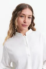 Camisa azul de manga larga con cuello mao, corte holgado y cierre frontal con botones.