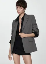 Blazer gris con raya diplomática, cuello con solapa, cierre frontal con botón y mangas largas abotonadas.