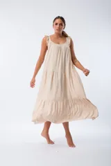 Vestido largo color beige, de corte recto, con breteles finos y volados en los hombros.