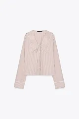 Camisa de popelina a rayas marrones y blancas, con cuello bobo con puntilla y escote pico con lazada. Manga larga con puño y cierre frontal con botones.