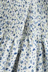 Vestido corto de popelina de algodón con estampado floral azul. Presenta escote cuadrado con elástico, mangas cortas abullonadas con fruncido elástico, cuerpo ajustado fruncido y falda con vuelo.