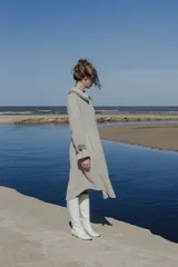 Tapado amplio color gris claro, confeccionado en lana fina sin teñir. Tiene hombros caídos, mangas largas con presillas y detalle de color en el cuello.