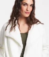 Cardigan alargado color blanco, con cuello virada, forro de pelos y confeccionado en punto pesado. No tiene cierre.