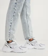 Zapatillas deportivas blancas con detalles en plateado y azul marino, de estilo chunky y suela gruesa.