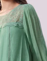 Blusa verde agua de gasa con cuello redondo y aplique de crochet. Tiene mangas 3/4 amplias con puño y botón, y forro interno a tono.