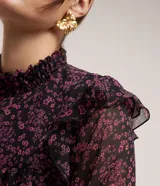 Blusa de chiffon negra con estampado floral liberty en tonos rosados, cuello alto con lastex y volados en los hombros. Mangas largas con puños ajustados.