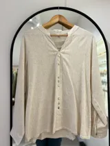 Blusa beige de manga larga regulable, con escote en pico y botones en la parte delantera.