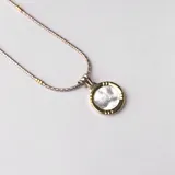 Conjunto de collar y dije circular en plata y oro con incrustación de nácar.