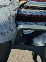 Chaleco calado negro con diseño de rayas diagonales rojas, beige y blancas.