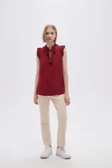 Blusa sin mangas color crudo con cuello con lazo y volados en los hombros.