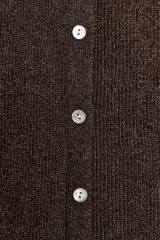 Top de punto acanalado en color beige, sin mangas y con cuello redondo. Presenta un cierre frontal con botones pequeños y un bajo con acabado en peplum que aporta volumen.