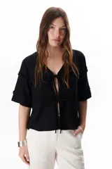 Chaqueta color beige con escote en V y cierre frontal con lazos. Presenta mangas cortas con volados.