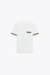 Camiseta blanca de corte slim fit, cuello redondo y manga corta. Detalle de acabados en tricot con hilo metalizado color dorado en mangas y bolsillo.
